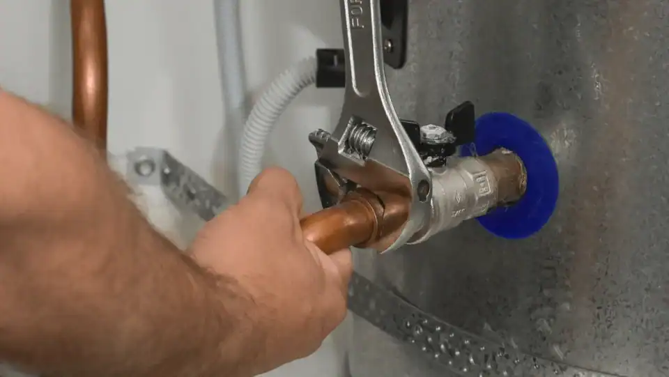 Hand tightening copper pipe with wrench on water heater